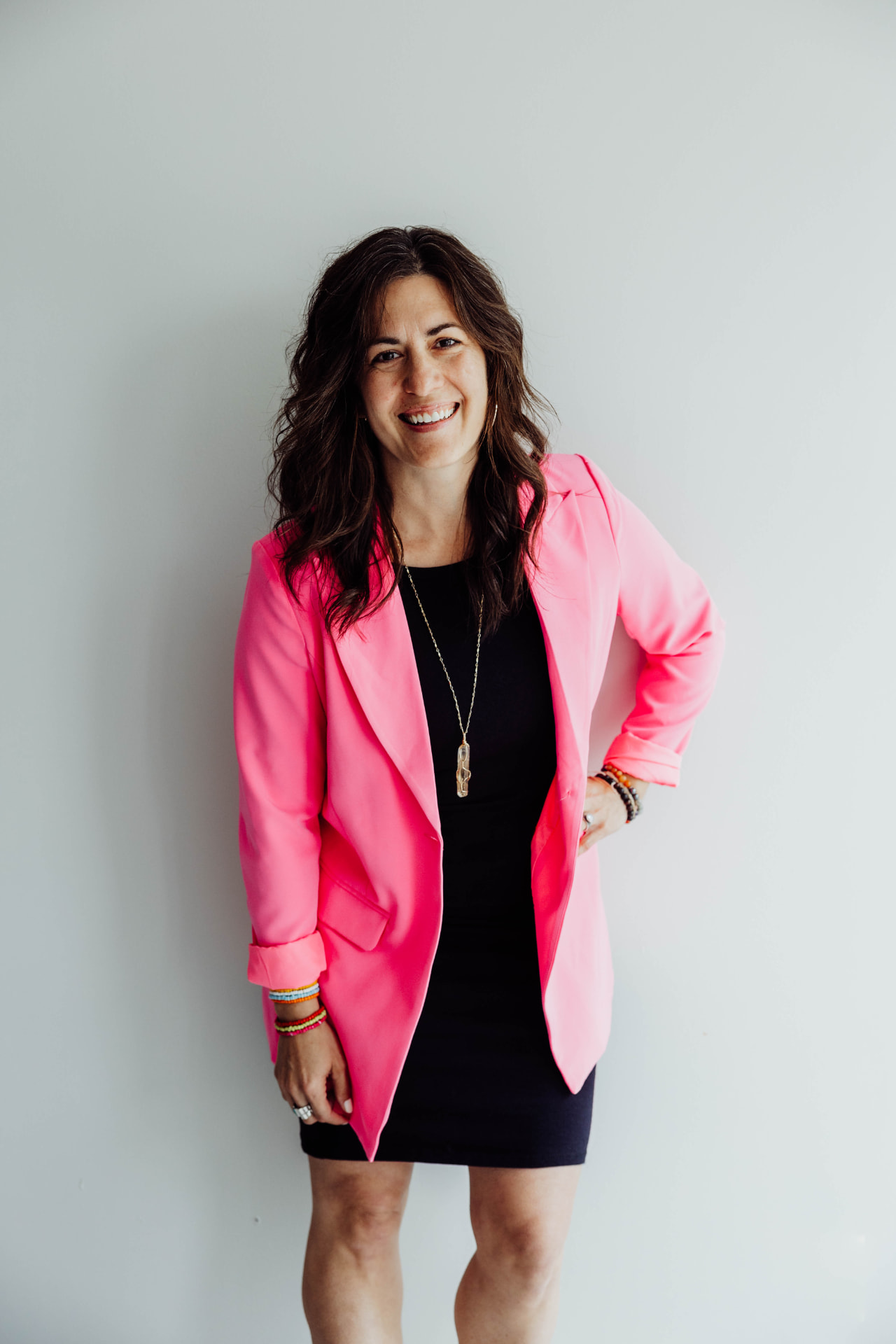 Ashli Freesmeyer in a pink blazer over a black dress, smiling at the camera