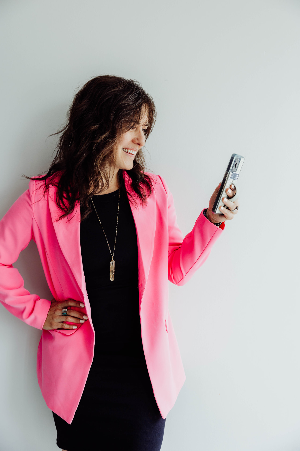 Ashli Freesmeyer in a pink blazer, smiling at her phone