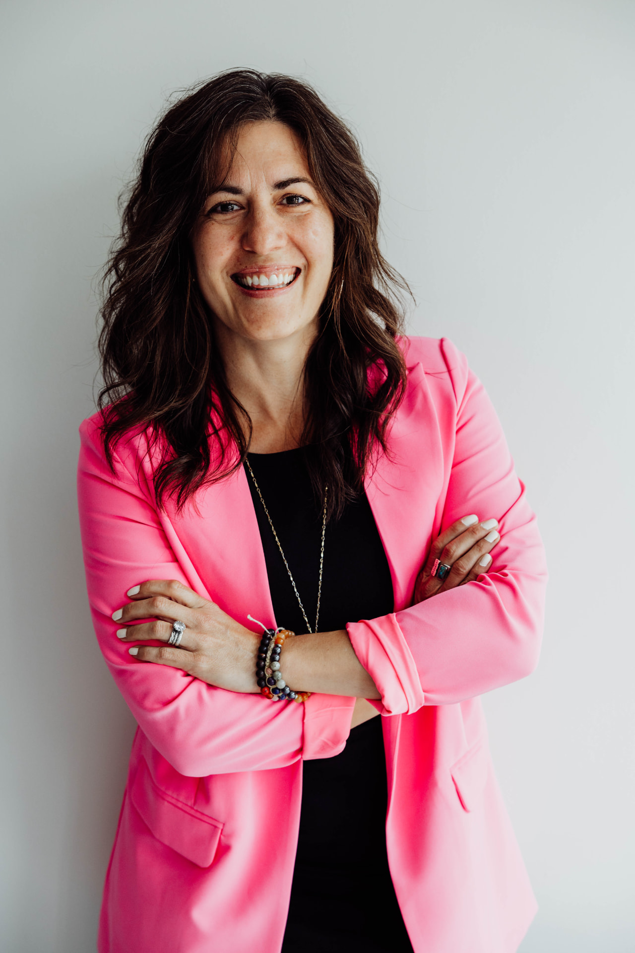 Ashli Freesmeyer in a pink blazer, arms crossed, smiling at the camera